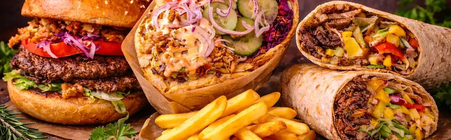 Double burger, filled wraps and french fries arranged together.