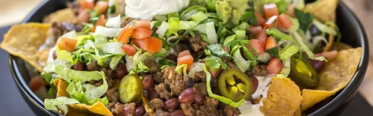 Loaded nachos topped with seasoned meat, lettuce, tomatoes, jalapeno slices, beans and sour cream.