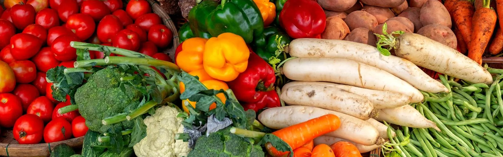 Assorted fresh vegetables including tomatoes, peppers, carrots, green beans, broccoli and cauliflower.