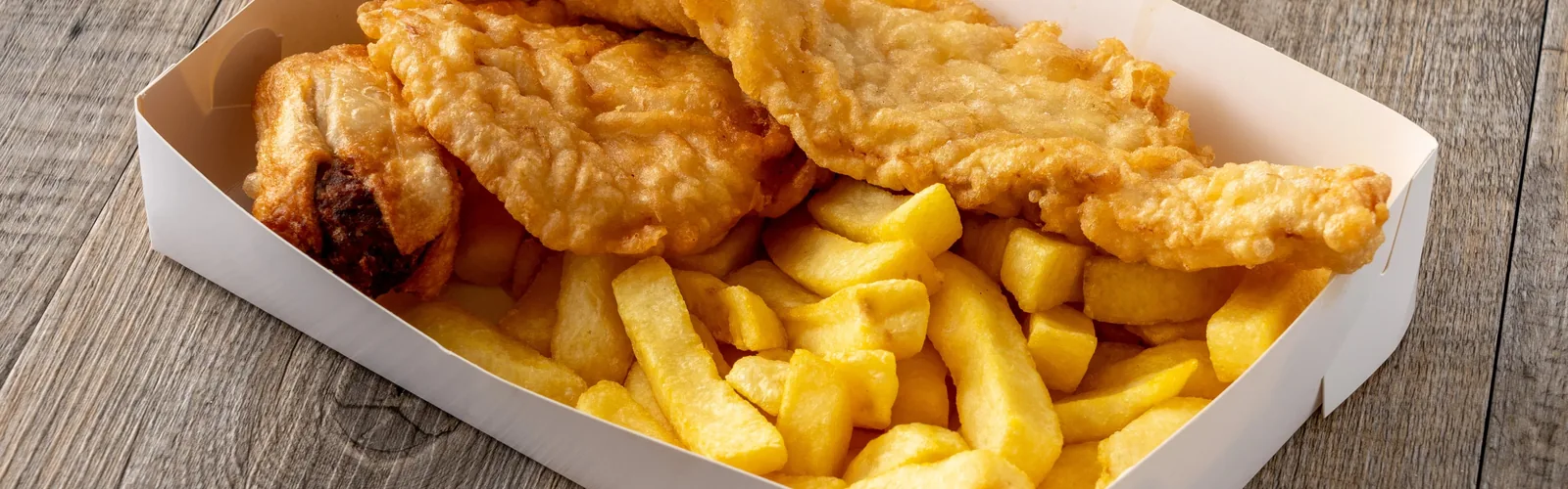 Battered fish and thick-cut chips served in a cardboard carton.