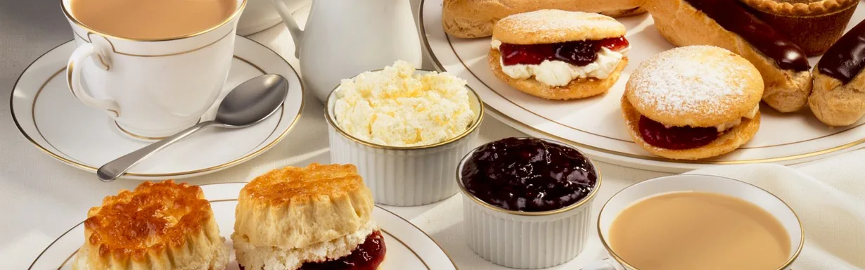 Afternoon tea spread with scones, cakes and teacups
