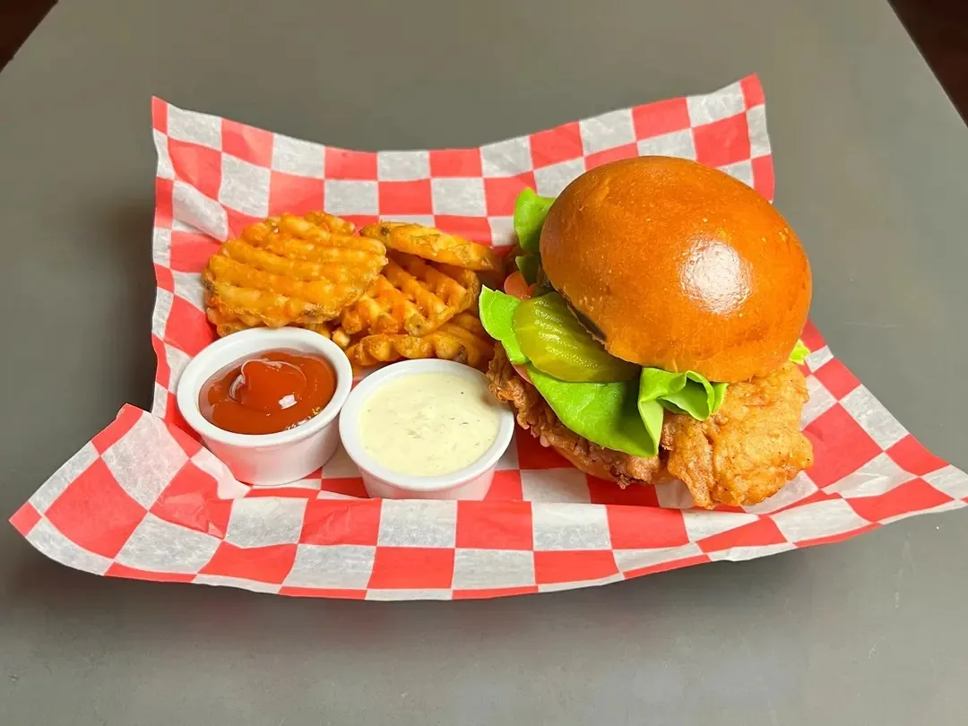 Crispy chicken sandwich and waffle fries in a basket