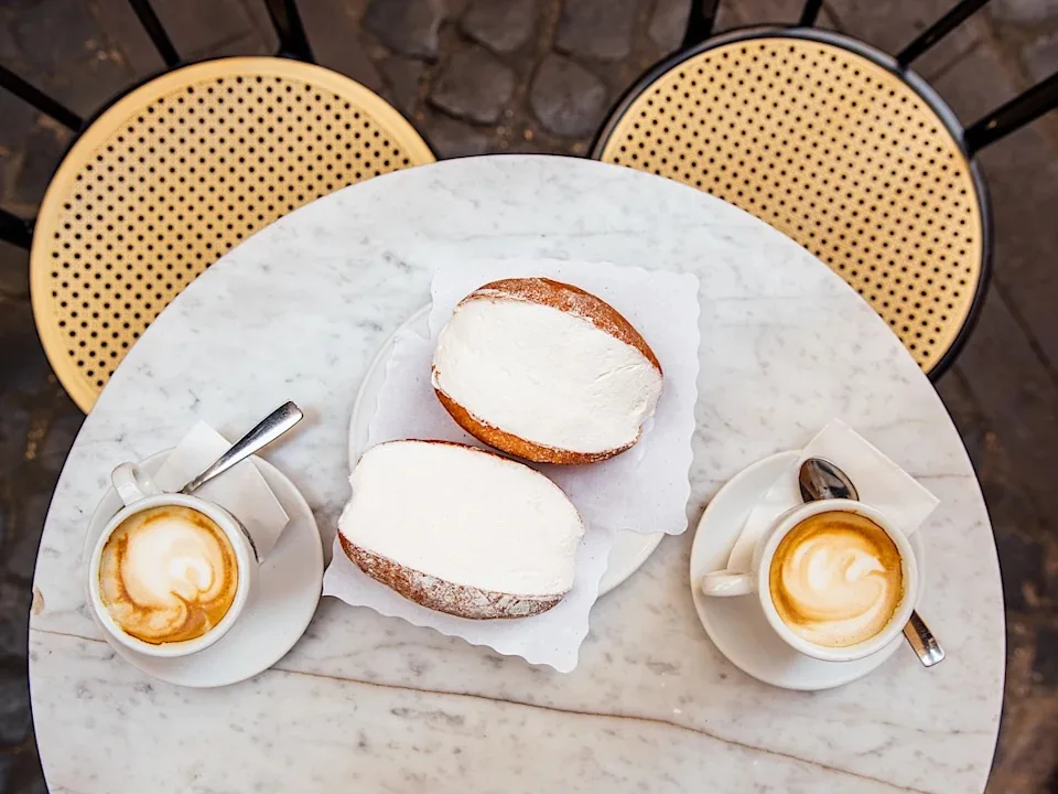 Cappuccinos with latte art and pastries on a cafe table