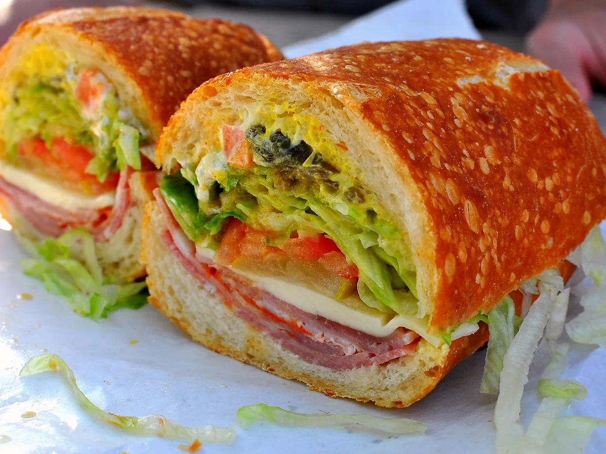 Deli sub sandwich cut showing ham, cheese, lettuce and tomato