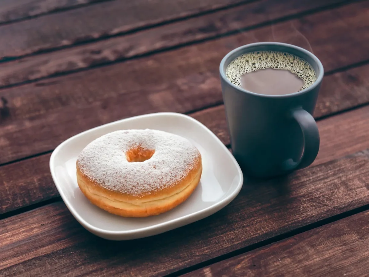 Powdered donut and coffee mug on a wooden table