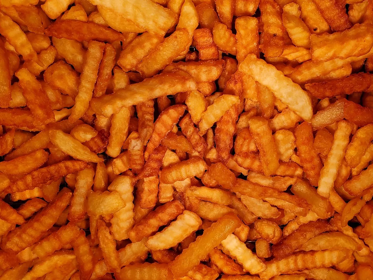 A close-up pile of golden crinkle-cut French fries.
