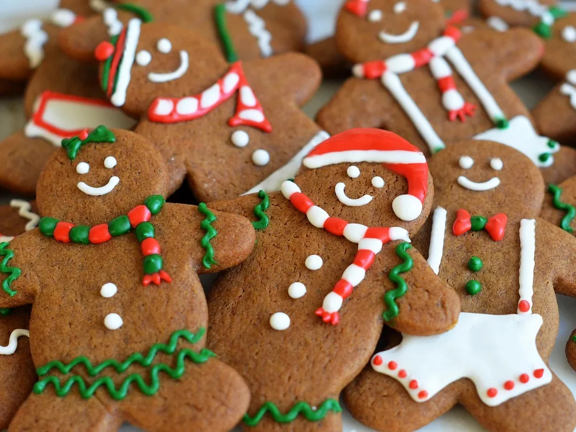 Decorated gingerbread biscuits shaped like people, with red, green, and white icing.
