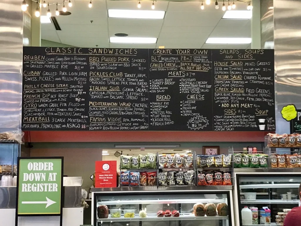 A dark chalkboard menu with handwritten food and drink items and prices.
