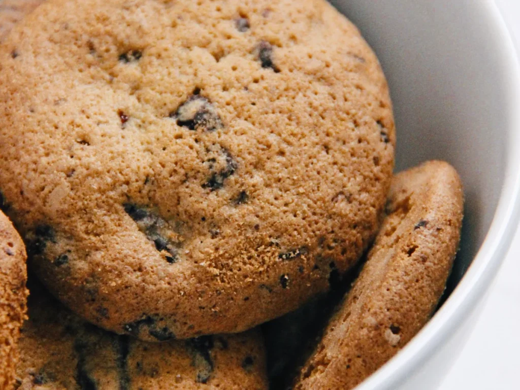 Chocolate chip cookies stacked in a white bowl.