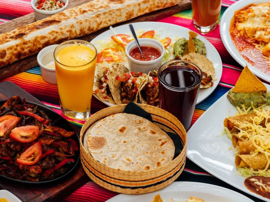 A colorful spread of tacos, tortillas, drinks, and other Mexican dishes on a table.