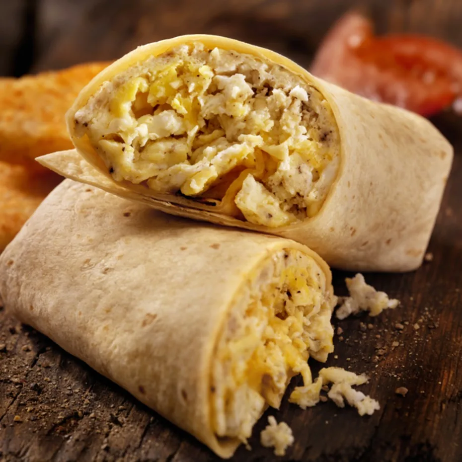 A breakfast burrito cut in half showing a scrambled egg filling.