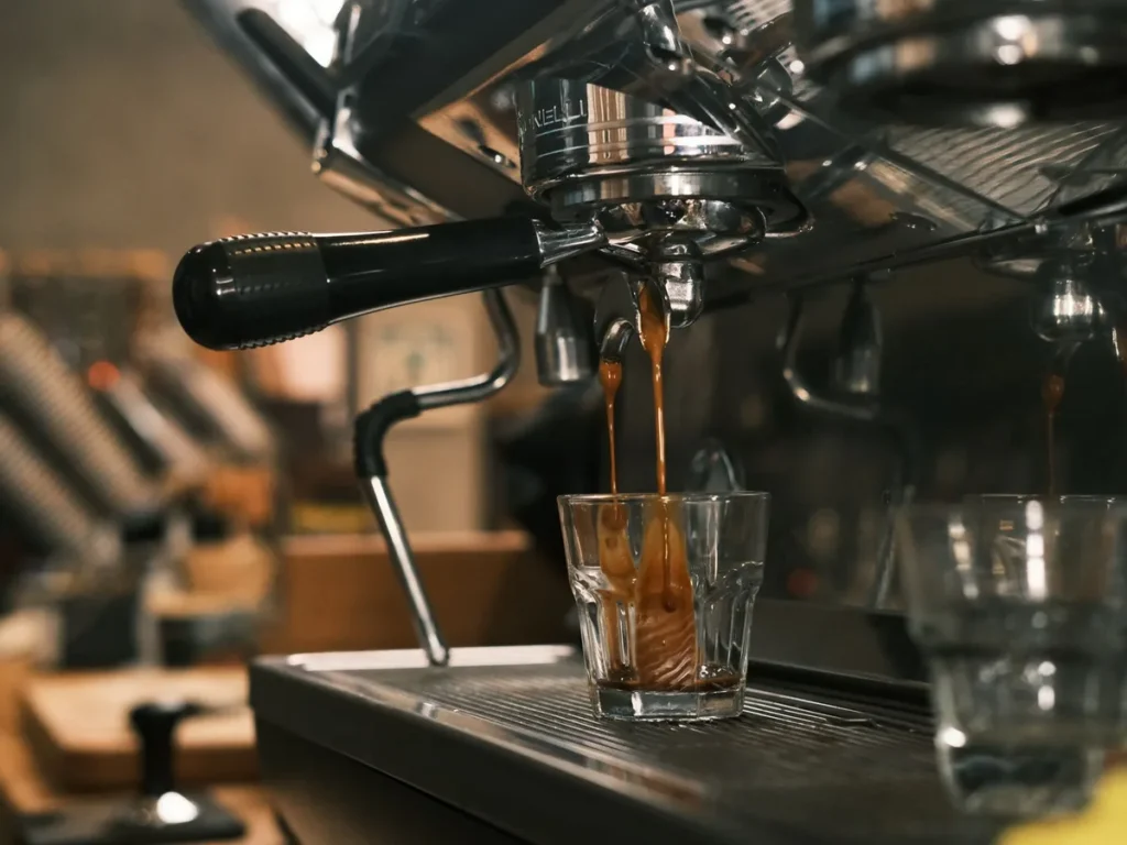 Espresso pouring from an espresso machine into a small glass.