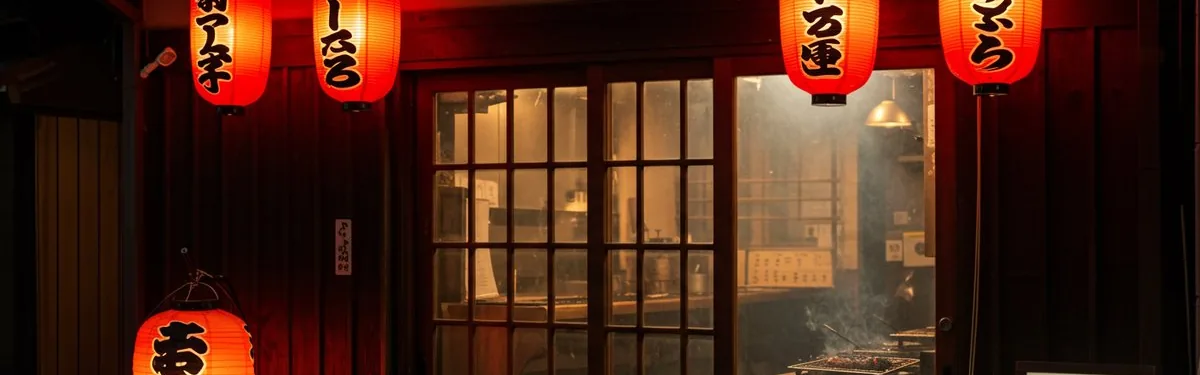 Red paper lanterns hanging outside a restaurant entrance with large glass doors at night.